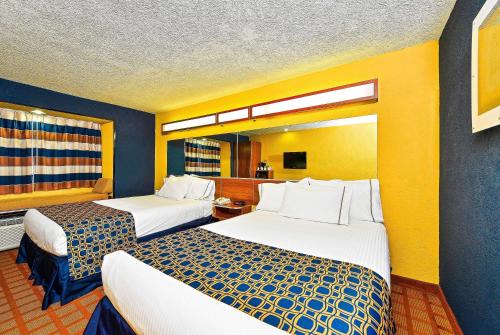 two beds in a hotel room with yellow walls at Microtel Inn & Suites by Wyndham New Braunfels I-35 in New Braunfels