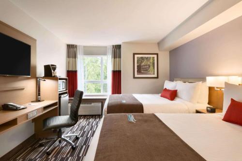 een hotelkamer met 2 bedden en een bureau bij Microtel Inn & Suites by Wyndham Oyster Bay Ladysmith in Ladysmith