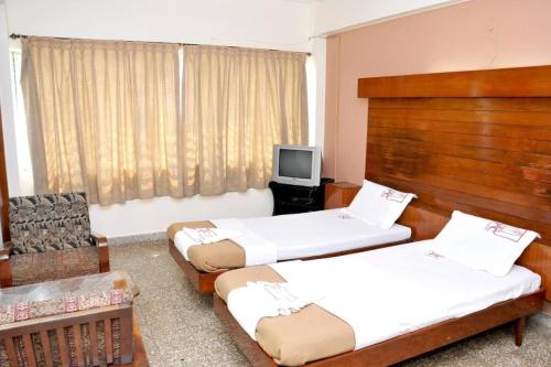 Habitación con 2 camas y TV. en PRANAM COMFORTS LODGE, en Bangalore