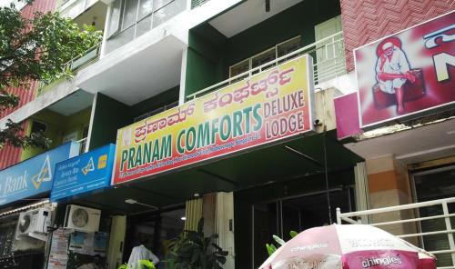 a building with signs and an umbrella in front of it at PRANAM COMFORTS LODGE in Bangalore
