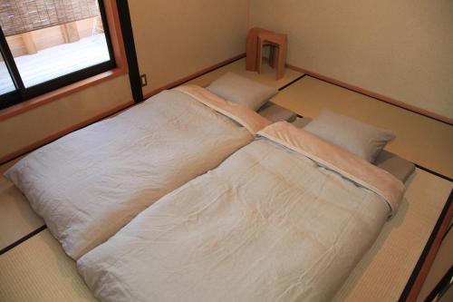 倉敷市にある暮らしの宿 てまり ゆきかいの窓付きの客室で、白い大型ベッド1台が備わります。