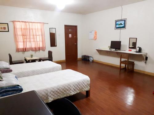 Cette chambre comprend 2 lits et un bureau. dans l'établissement Minine Guesthouse, à Silang
