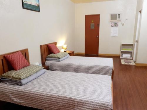two beds in a room with wood floors at Minine Guesthouse in Silang