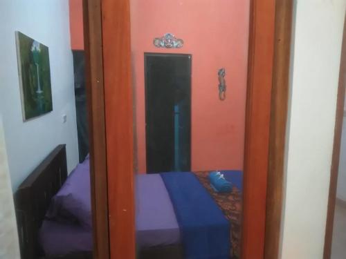 a door to a room with a bed and a mirror at Made Roejas Family in Uluwatu