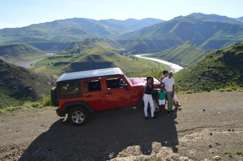 a group of people standing next to a red jeep at Motebong Lodge in Bokong