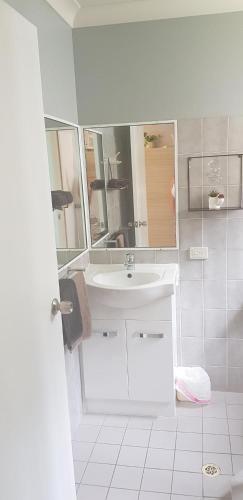a white bathroom with a sink and a mirror at Limassol Motel in Gold Coast