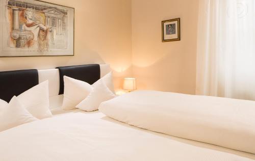 a bedroom with a large white bed with white pillows at Hotel Alpenrose in Bad Wörishofen