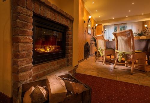 a fireplace in a living room with chairs and a table at Wohlfühlhotel Alpenrose in Bad Wörishofen