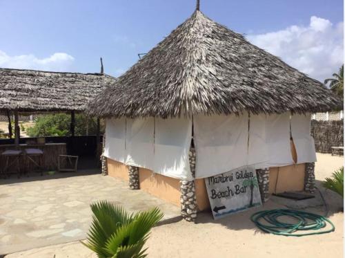a small hut with a straw roof on a beach at Mambrui Golden Beach Bar and Cottages in Mambrui