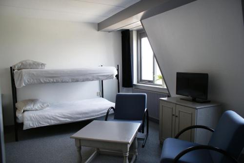 a room with two bunk beds and a table and a tv at Fletcher Hotel - Restaurant Nieuwvliet Bad in Nieuwvliet-Bad