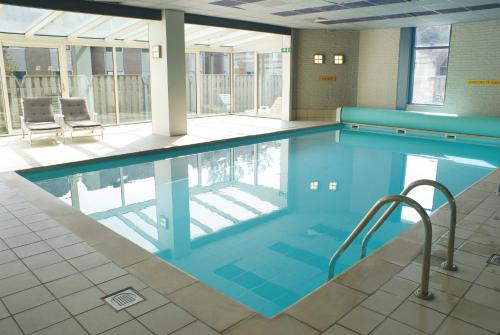 a large swimming pool in a building at Fletcher Hotel - Restaurant Nieuwvliet Bad in Nieuwvliet-Bad