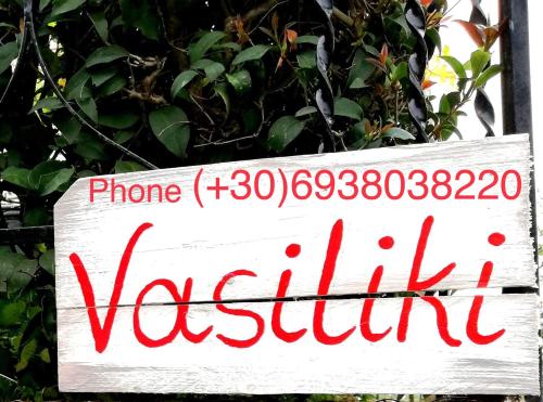 a white sign with red writing on a bush at Vasiliki Guest House in Kalamata
