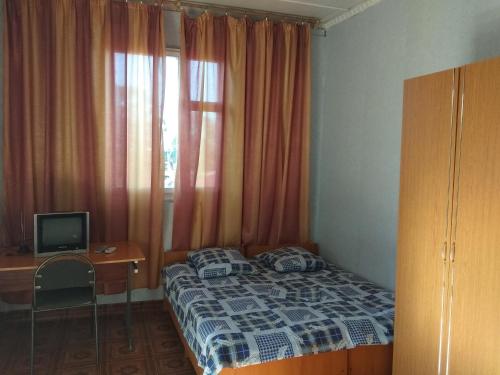 a bedroom with a bed and a desk with a television at Guesthouse on Kabardinskaya 139a in Gagra