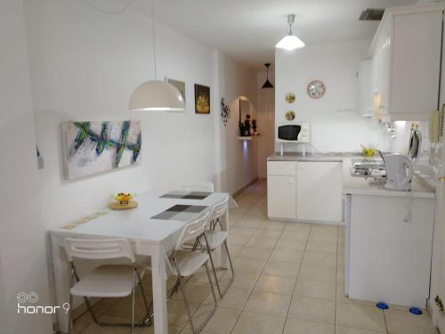 cocina blanca con mesa blanca y sillas en Casa Patrizia Playa San Juan, en Guía de Isora