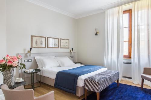 a white bedroom with a bed and a blue rug at Favilla Hotel di Charme in Rome