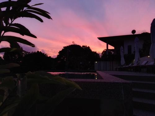 a sunset over a house with a swimming pool at Ranis Lodge in Kampung Padang Masirat