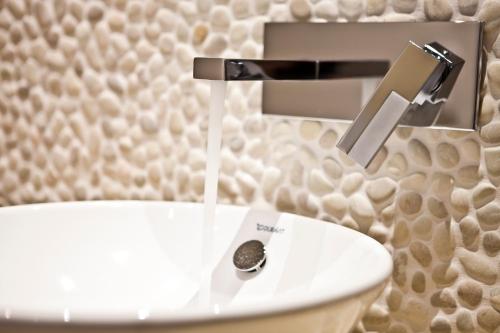 a white toilet with water coming out of a faucet at Hotel 54° Nord in Hörnum