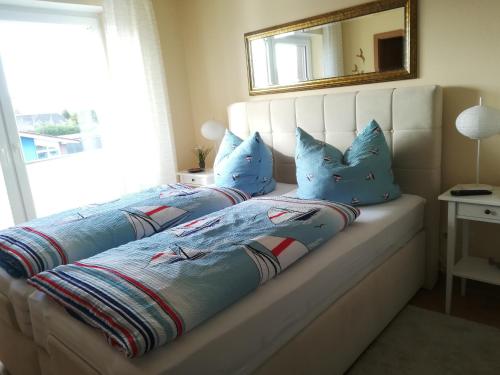 WeenerにあるKäptn's Kojeのベッドルーム1室(青い枕と鏡付きのベッド2台付)