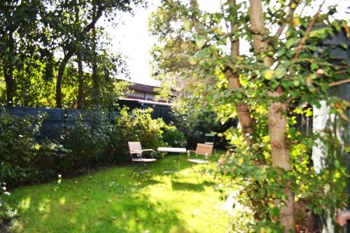 a garden with two benches and a table and a tree at Deichblick in Utersum