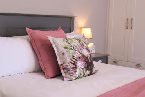 een bed met roze en witte kussens erop bij Brookshill - Protea suite in Somerset West