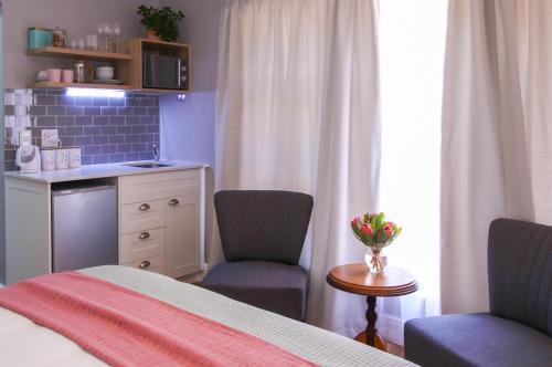 een slaapkamer met een bed en 2 stoelen en een tafel bij Brookshill - Protea suite in Somerset West