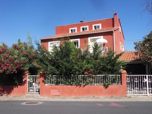 a red house with a white fence and flowers at Chambres d'Hôtes de la Grone in Argelès-sur-Mer