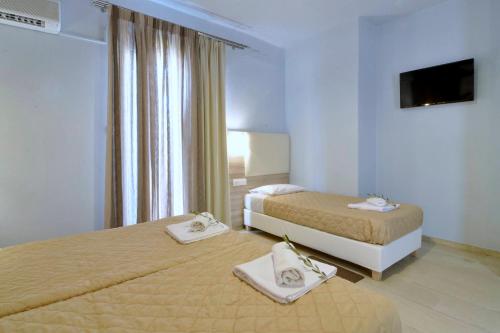 a hotel room with two beds and a television at Hotel Orpheus in Gouvia