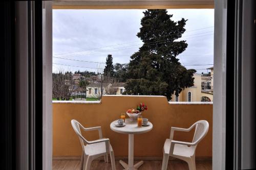 a table and chairs on a balcony with a window at Hotel Orpheus in Gouvia