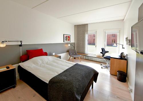 a bedroom with a bed and a desk and a chair at Pharmakon Hotel & Conferencecenter in Hillerød