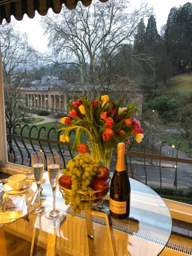 uma mesa com uma garrafa de vinho e uma taça de fruta em Reichel-Appartements em Baden-Baden