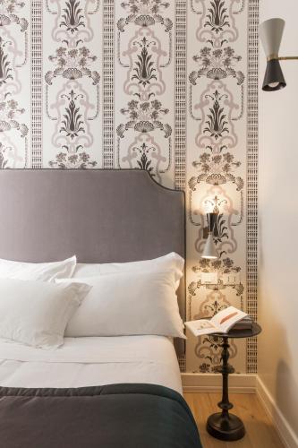 a bedroom with a bed and a wall with wallpaper at Favilla Hotel di Charme in Rome