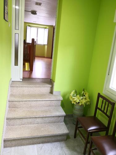 a hallway with green walls and stairs with a chair at Casa Carlán in Melide