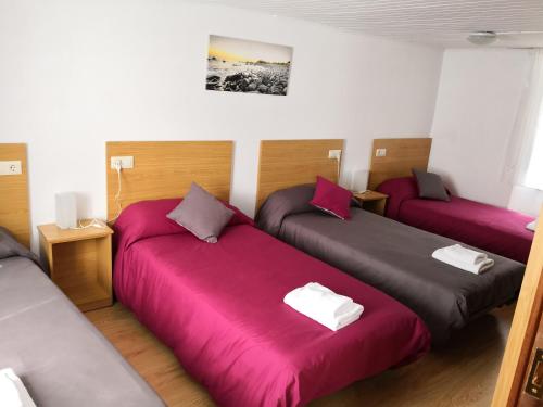 um quarto com três camas com lençóis cor-de-rosa em Casa Carlán em Melide