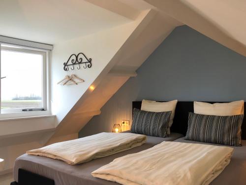 a attic bedroom with two beds and a window at Fila Stroo in Kamperland