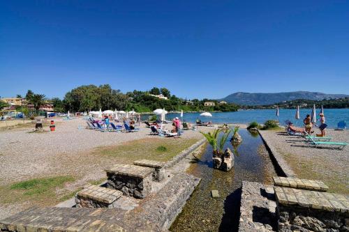 a group of people sitting on a beach near the water at Hotel Orpheus in Gouvia