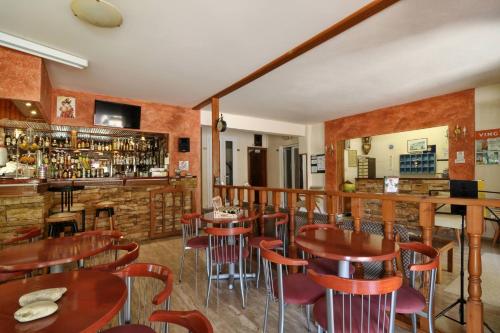 a restaurant with wooden tables and chairs and a bar at Hotel Orpheus in Gouvia