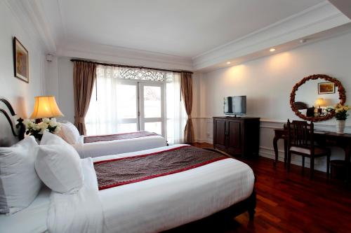 a hotel room with two beds and a desk and a television at Dhavara Boutique Hotel in Vientiane