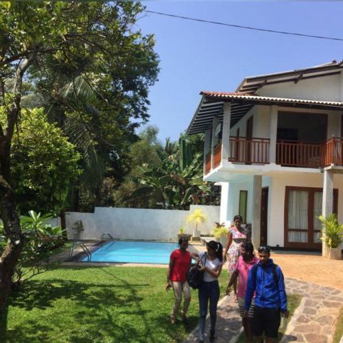 a group of people standing in front of a house at Blue Water hikkaduwa in Hikkaduwa