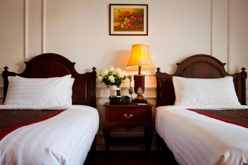 a bedroom with two beds and a lamp on a night stand at Dhavara Boutique Hotel in Vientiane