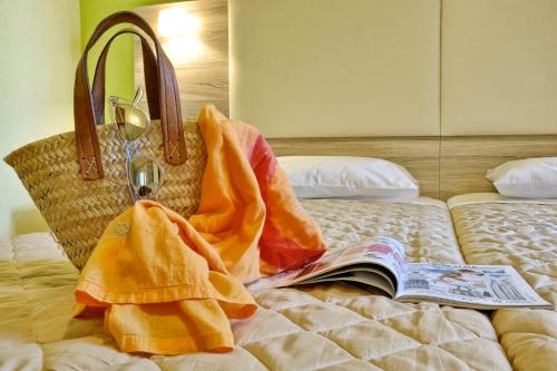 a bed with a book and a purse on it at Hotel Orpheus in Gouvia