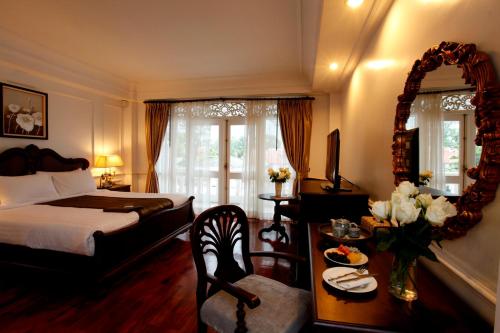 a bedroom with a bed and a table and a mirror at Dhavara Boutique Hotel in Vientiane