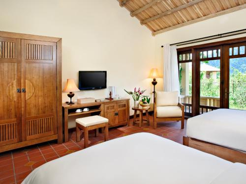 a bedroom with a bed and a desk and a tv at Emeralda Resort Ninh Binh in Ninh Binh