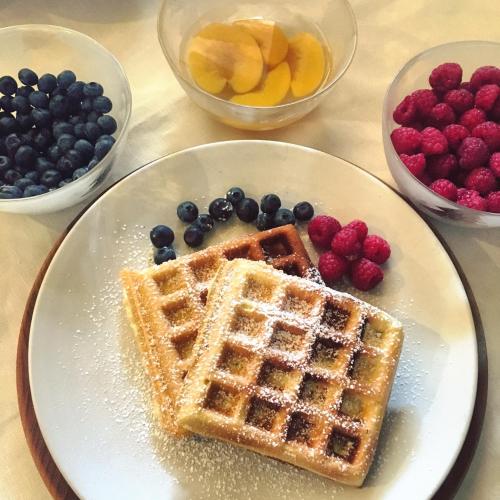 a plate with waffles and berries and bowls of fruit at Confrérie du Moyen Âge in Verrayes