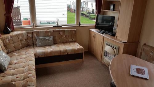 a living room with a couch and a tv and a table at Silver beach 3 in Ingoldmells