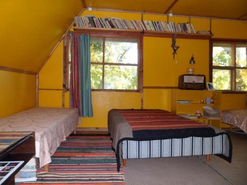 two beds in a room with yellow walls and windows at Viruna Farm in Kiraste