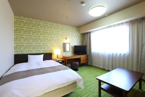 a bedroom with a bed and a tv and a window at Hachinohe Grand Hotel in Hachinohe