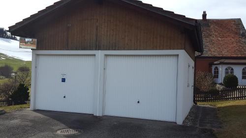 two white garage doors in front of a house at Ferienwohnung Eisenring in idyllischer Umgebung in Gähwil