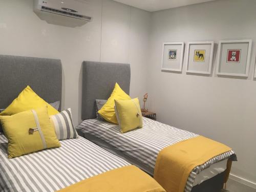 two beds with yellow pillows in a room at Pebble Beach Sibaya No.122 in Sibaya