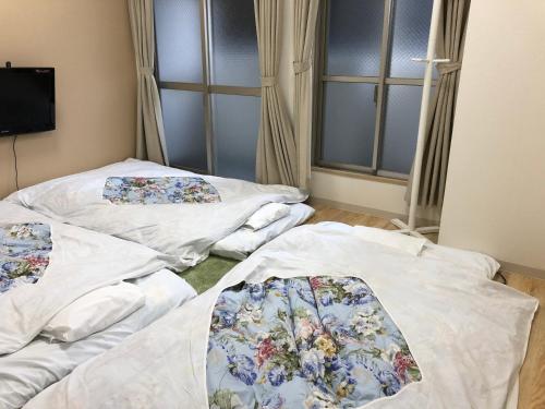 ein Zimmer mit drei weißen Betten mit Blumen darauf in der Unterkunft Hotel Mirai in Yokohama