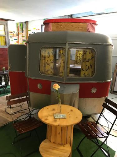 Ein alter Wohnwagen mit einem Tisch und einer Blume darauf. in der Unterkunft HafenTraum IndoorCampingHostel in Bremen